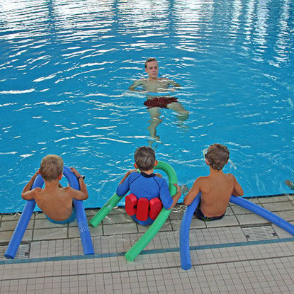Kinder hören dem Trainer zu und sitzen mit ihren Schwimmnudeln am Beckenrand